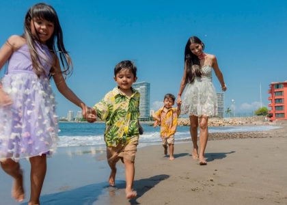 Cheerful family playing and running on a sunny beach, enjoying a vacation day together.